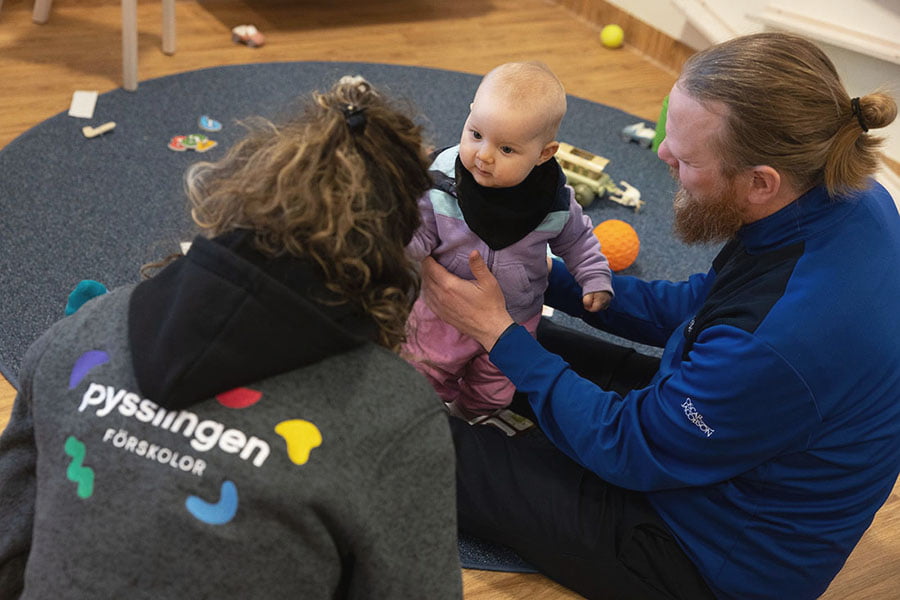 pappa, baby och pedagog sitter på golvet och pratar
