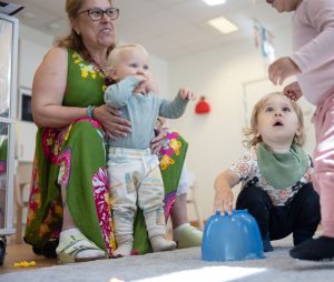 sittande kvinna med lekande barn på förskolan