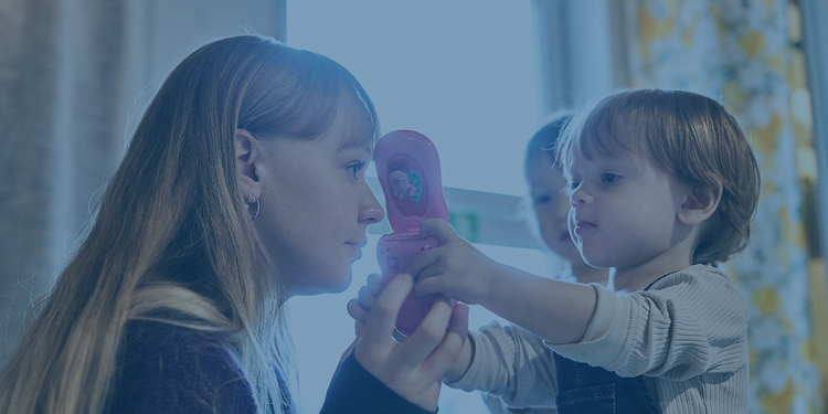 Pedagog och två barn leker med låtsastelefon.
