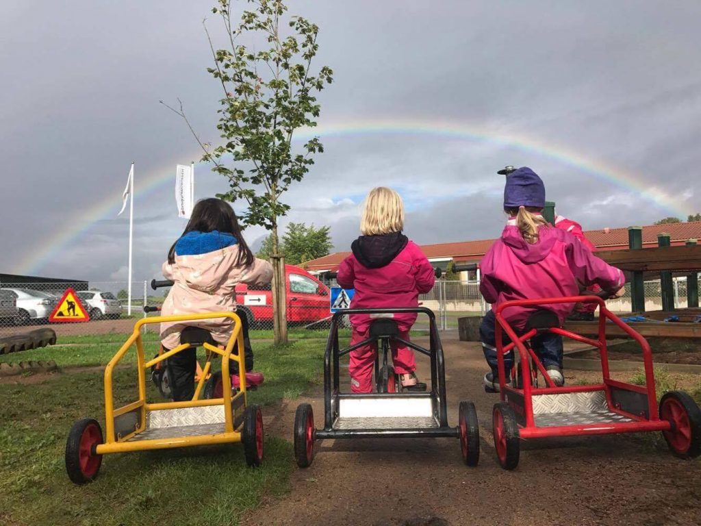 Tre barn cyklar på rad på gården.