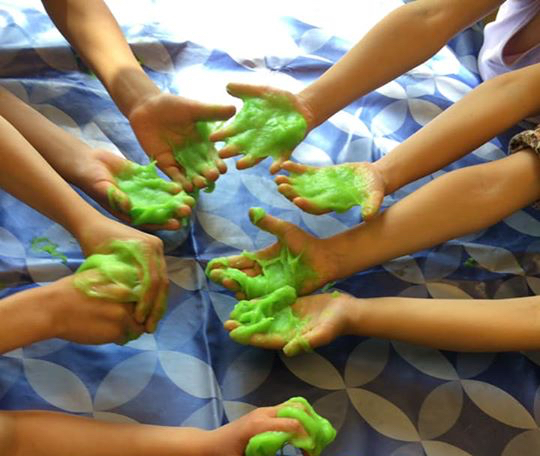 Händer fulla med grönt slime.