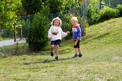 Barn spelar fotboll utomhus.
