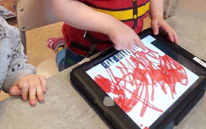 Barn ritar med röd penna på iPad