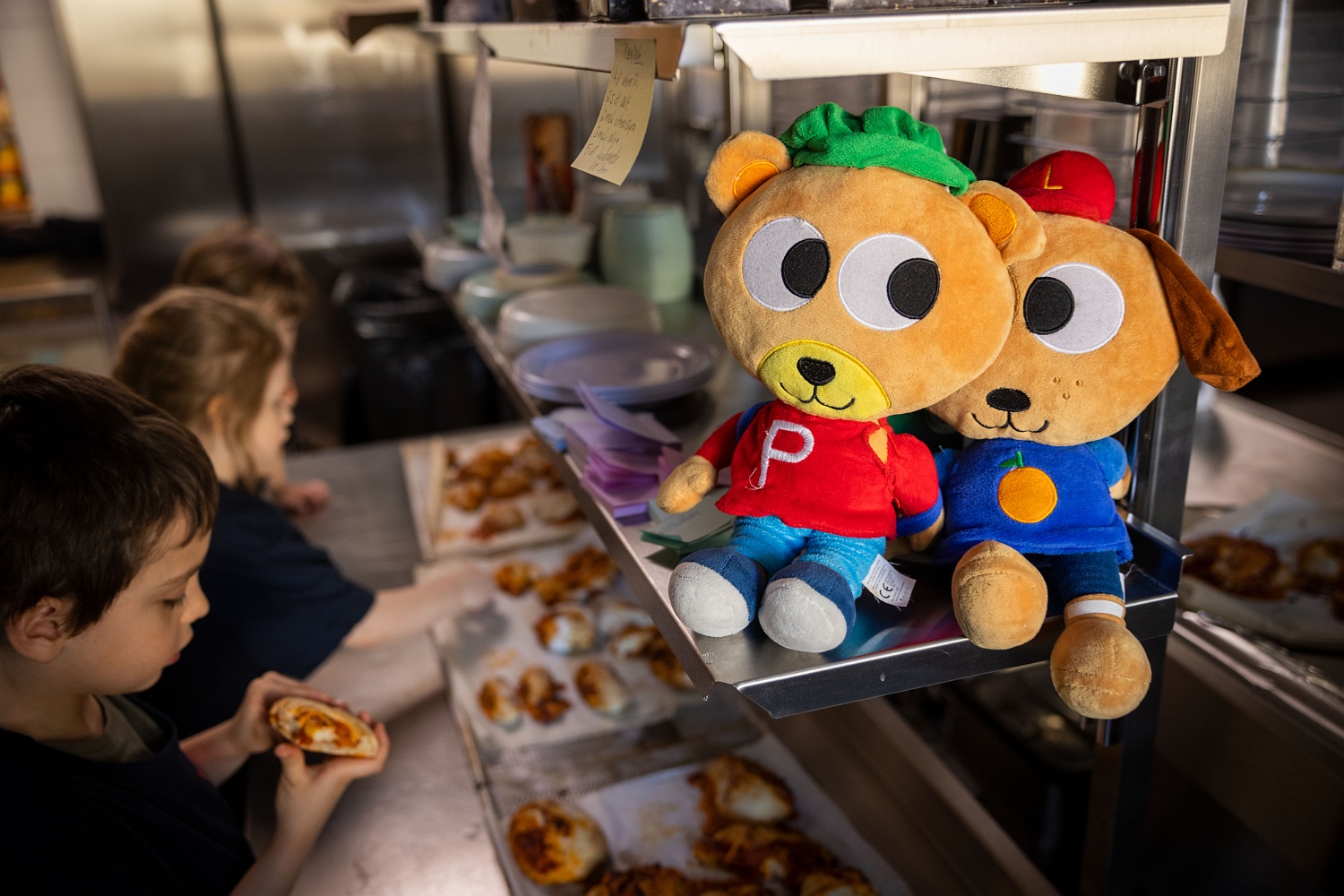 Barn äter pizzabullar i köket, Pyss och Ling syns på en hylla.