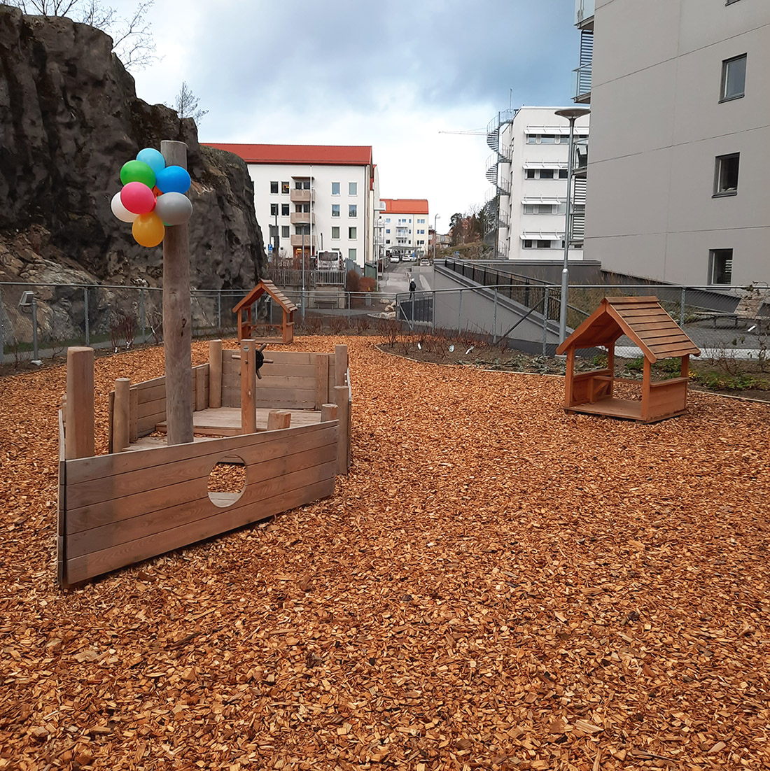träbåt med ballonger och två små trähus ute på förskolegård