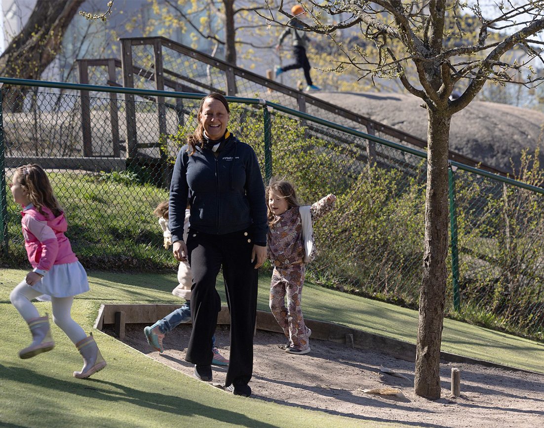 pedagog och springande barn ute på förskolegård