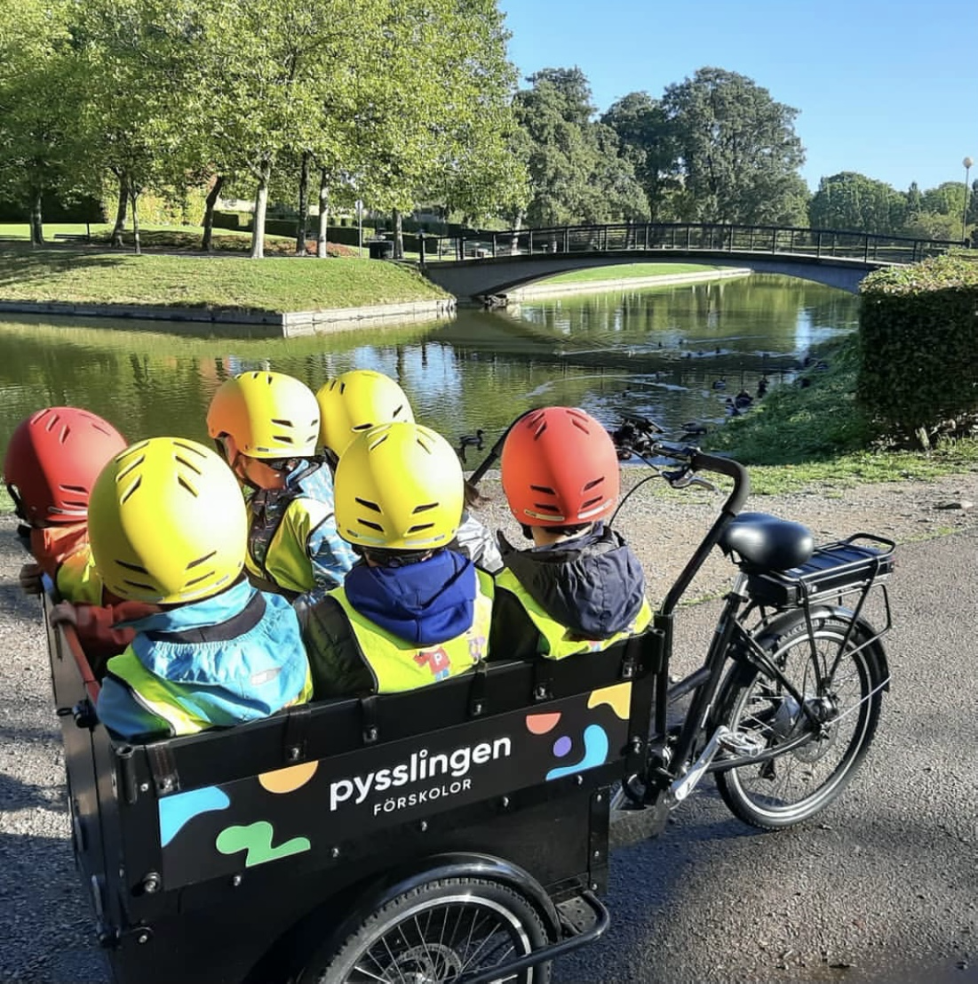 Barn sitter i en cykelvagn framför en sjö.