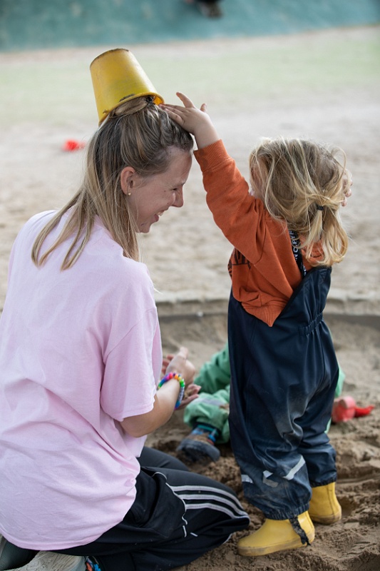 Barn busar med pedagog i sandlådan.