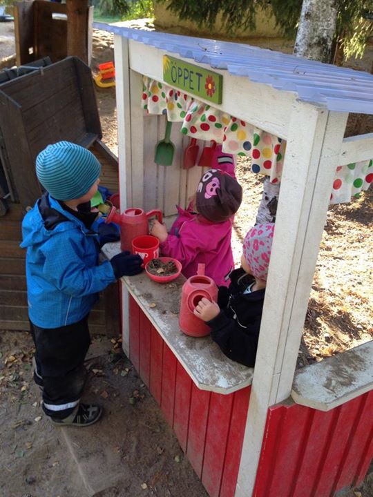 Barn leker kiosk ute på gården.