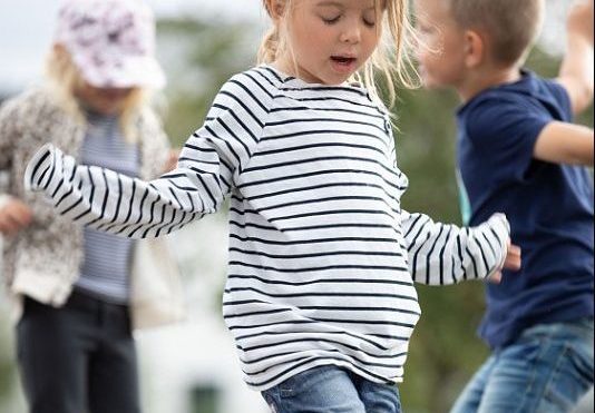 flicka som dansar ute med andra barn i bakgrunden