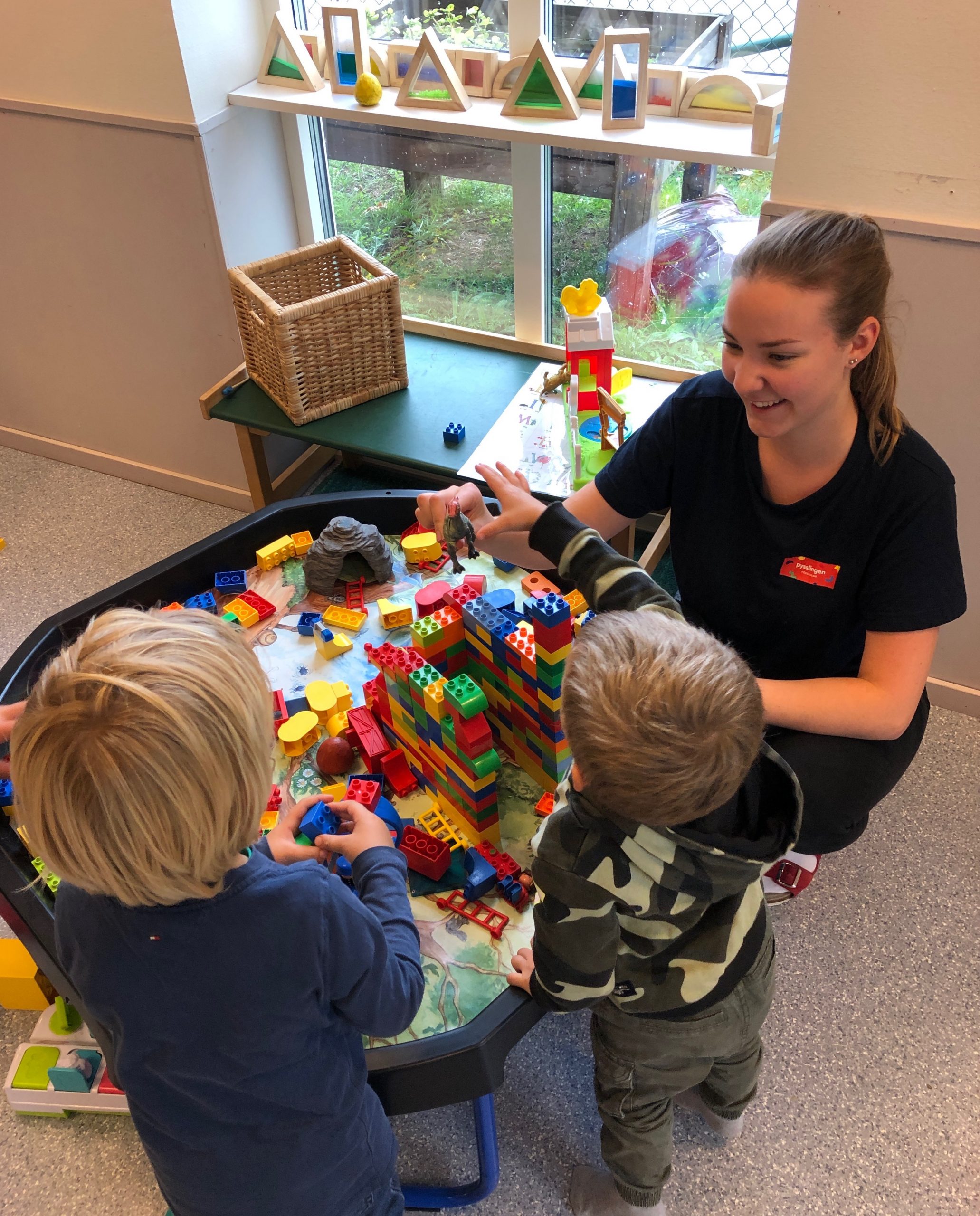 Pedagog och två barn leker med lego.