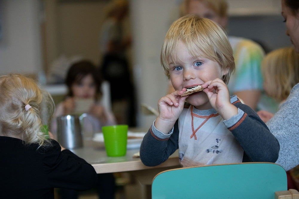 Pojke äter en knäckemacka under mellanmålet.