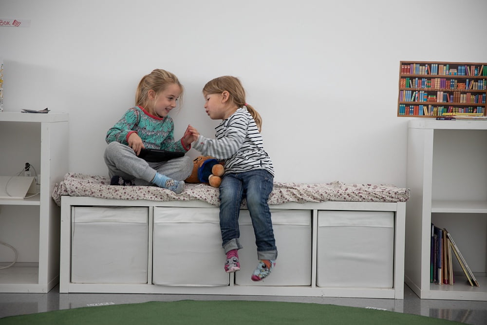 bild av två flickor som sitter på en bänk och pratar inne på förskolan