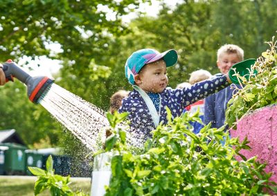 Barn vattnar odlingar på förskolans gård