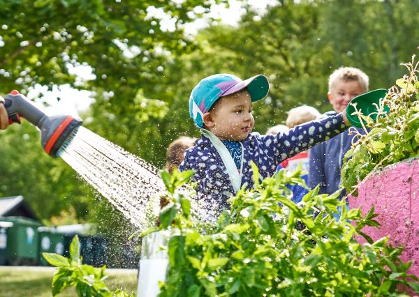 Barn vattnar odlingar på förskolans gård