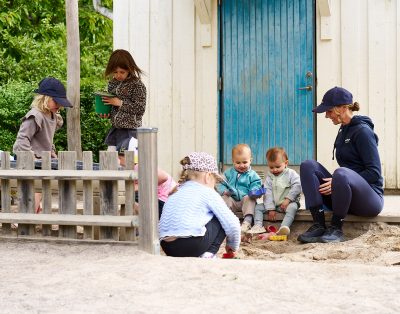 barn och pedagog leker i sanden på förskolan
