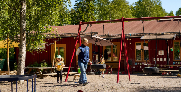 Barn och pedagog leker på utegården.