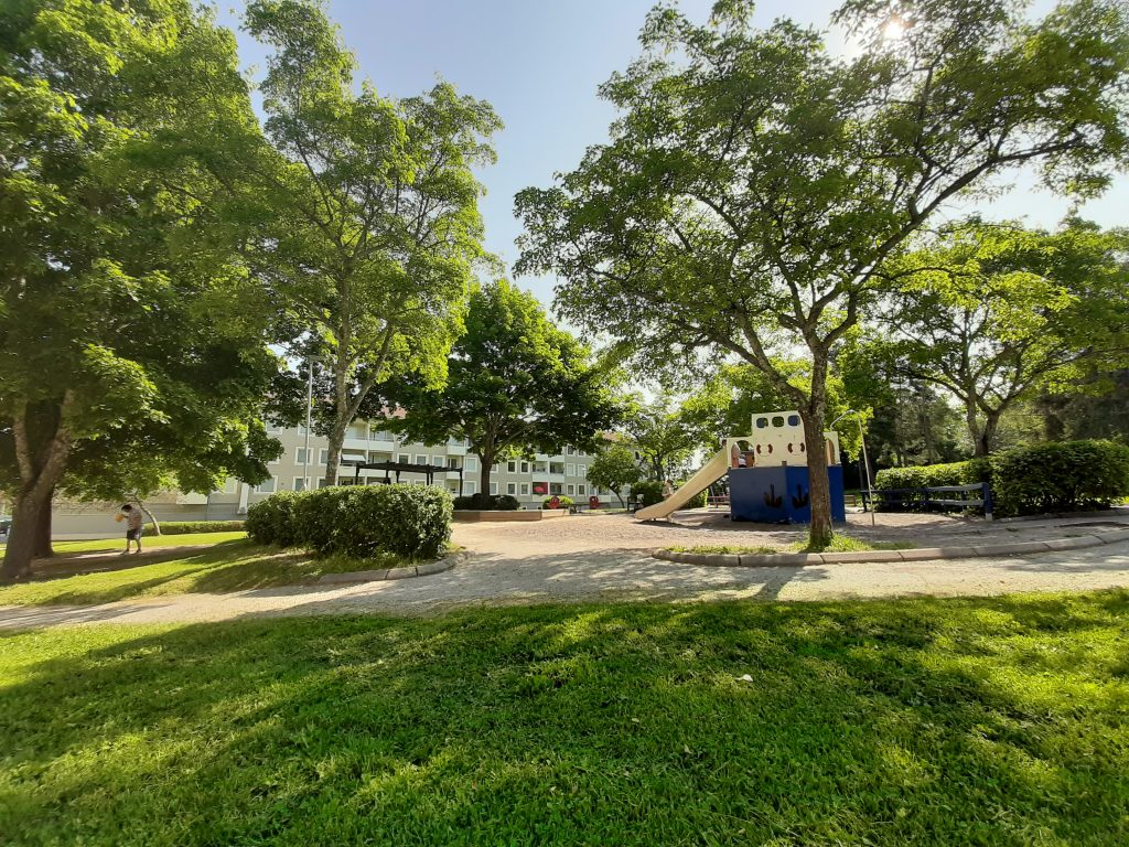 I en park som blommar, på håll syns ett lägenhetshus.