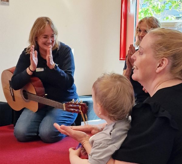 Vuxna och ett barn sitter tillsammans och sjunger och klappar