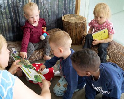 Barn och pedagog utforskar en bok tillsammans