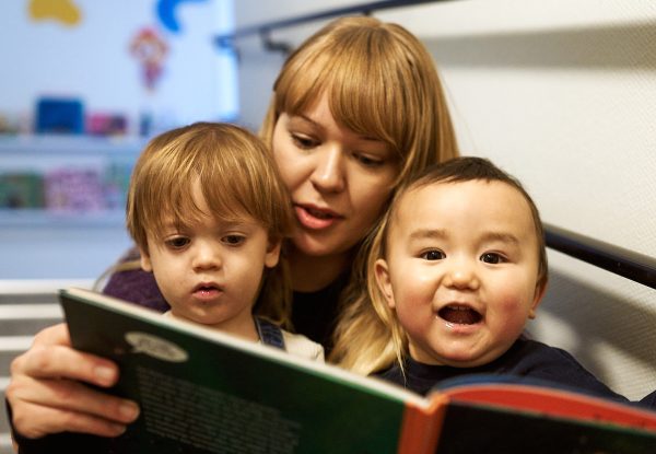 pedagog och barn läser bok tillsammans
