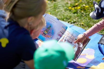 Barn och pedagog utforskar en bok utomhus