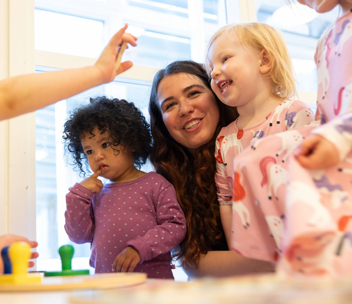 Glad pedagog spelar spel med två barn