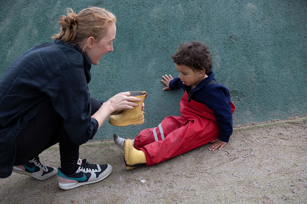 pedagog hjälper barn sätta på stövel pysslingen förskola