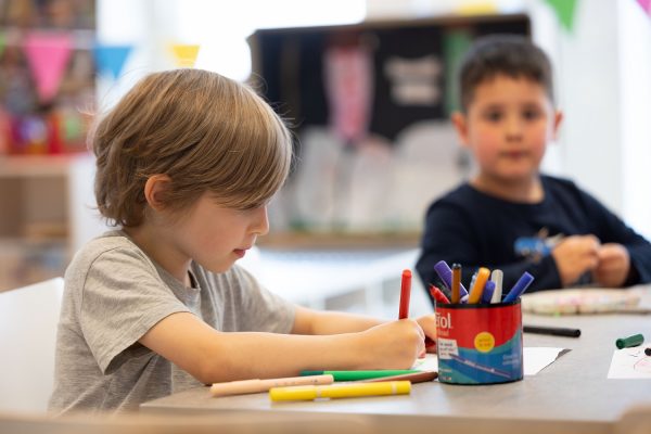 Pojke ritar med färgpennor.