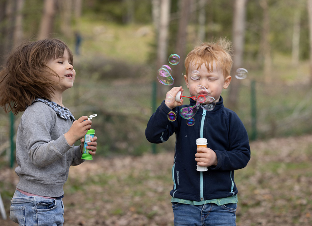 två barn blåser såpbubblor utomhus
