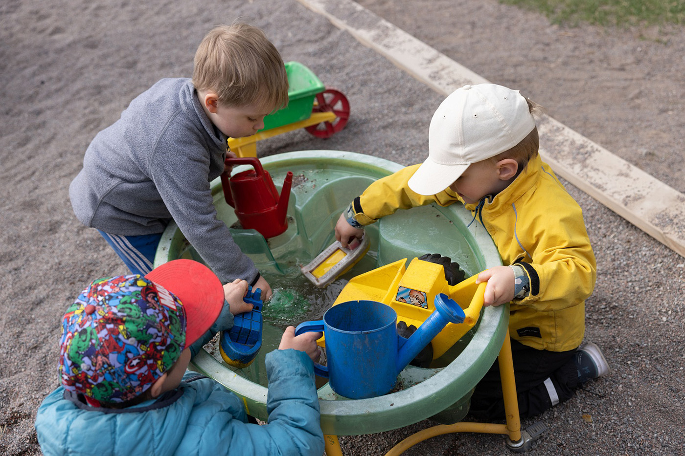 barn leker med vatten och leksaker i en balja utomhus